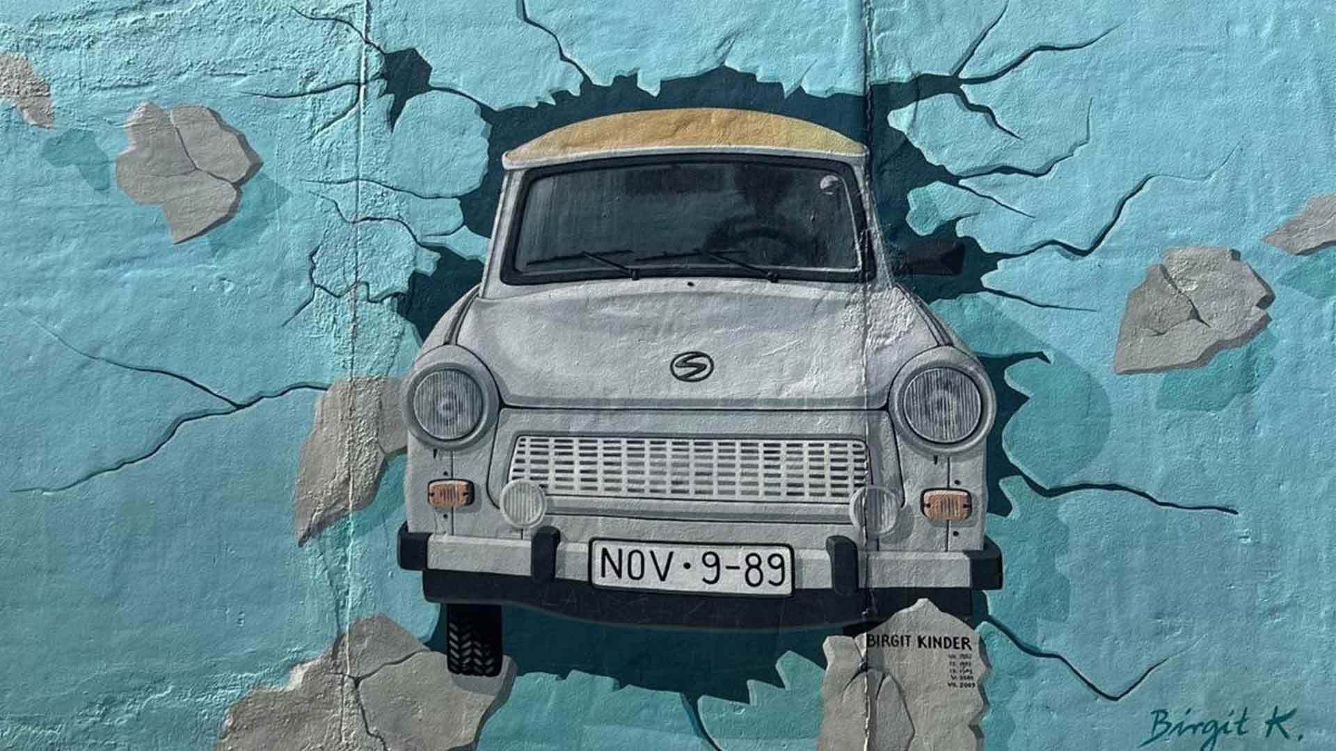 street art depicting a car breaking through a wall towards the viewer