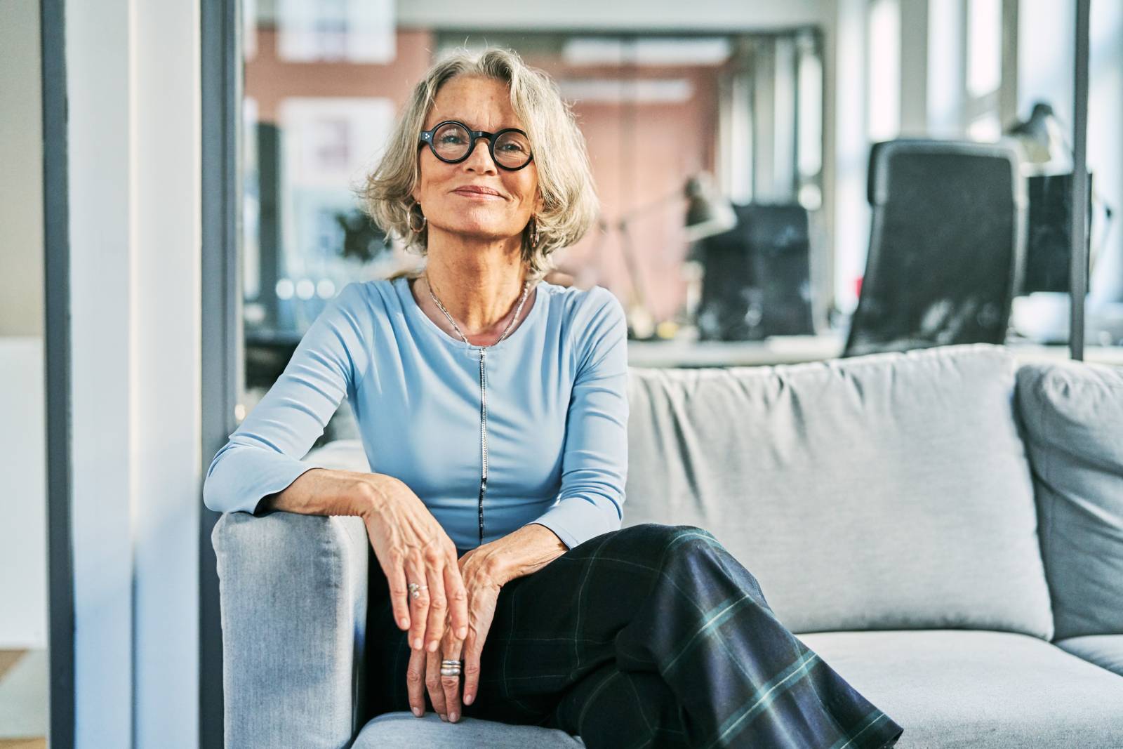 A lady sits on a sofa looking at the camera