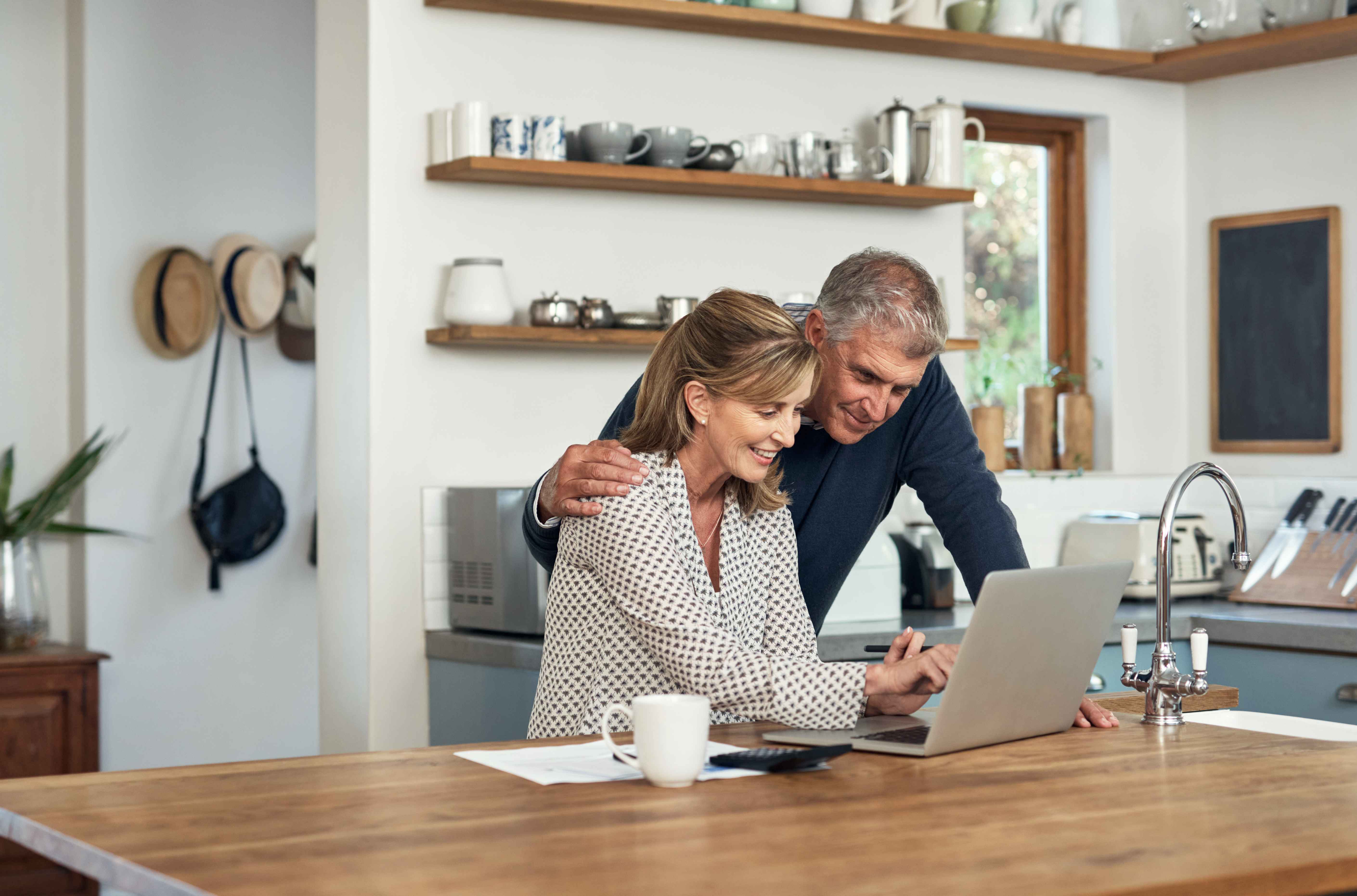 Couple looking excited at their laptop in the kitchen
