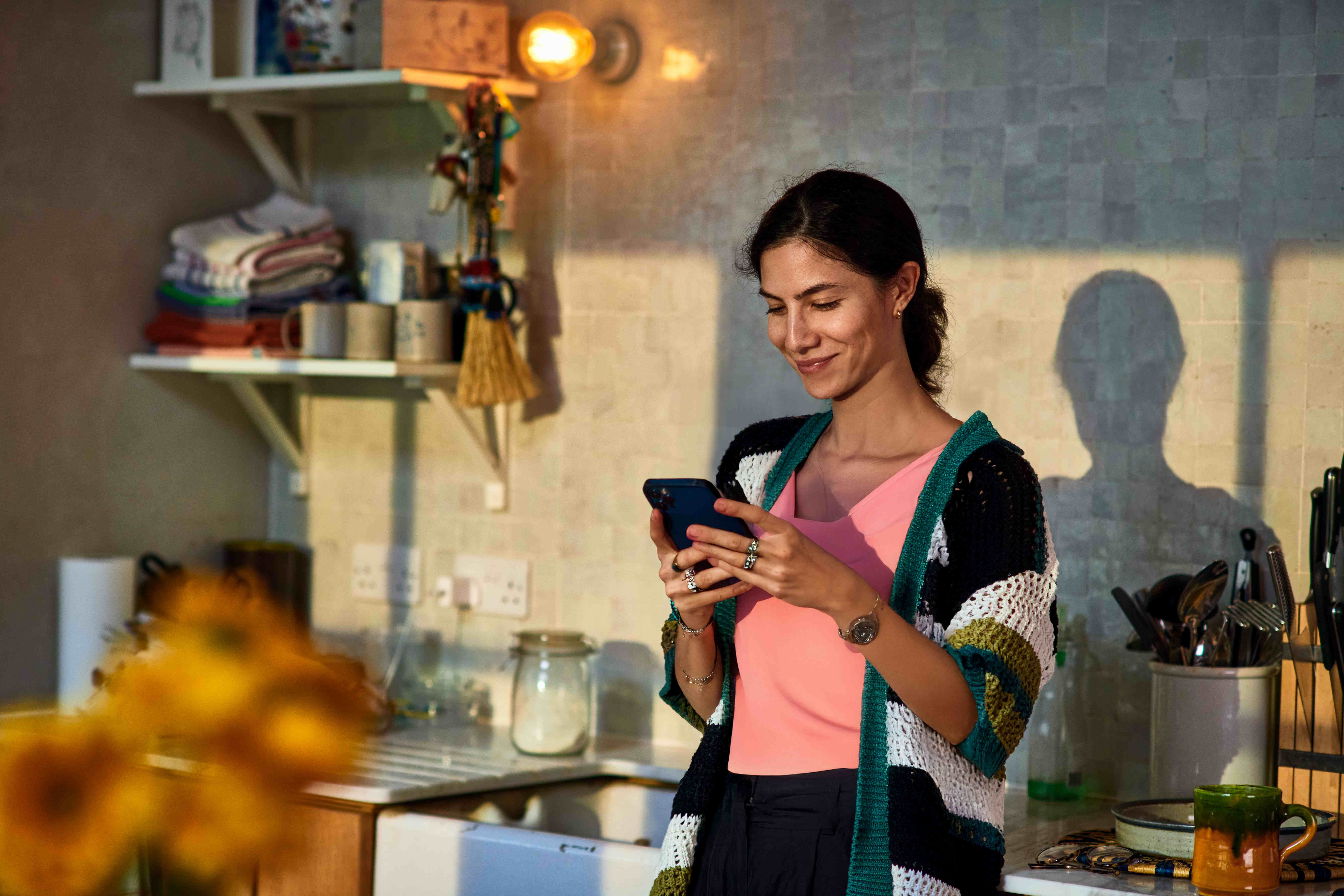 A young woman in her kitchen checks her phone