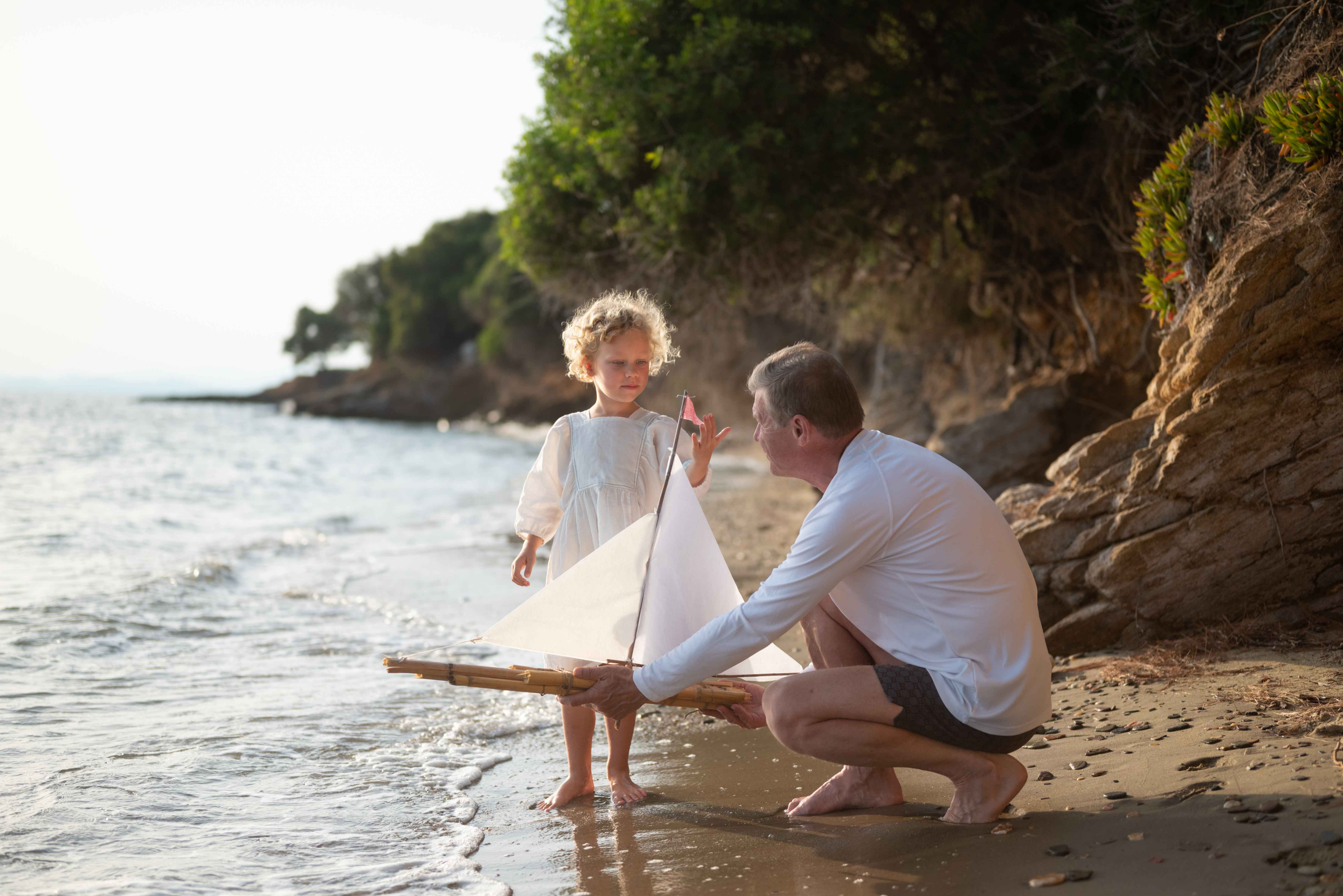 Father and daughter setting off a boat on the beach