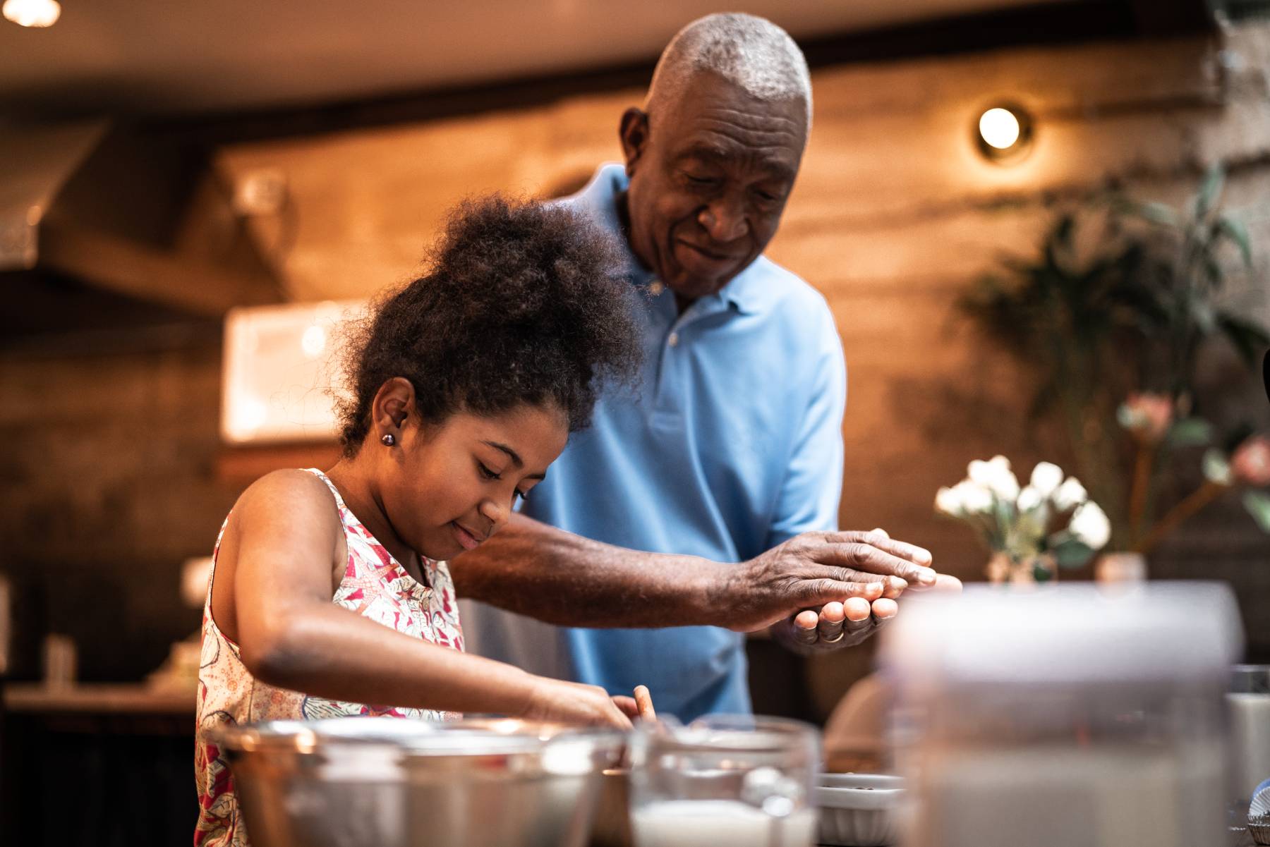 A grandfather makes a cake in the kitchen with the help of his granddaughter