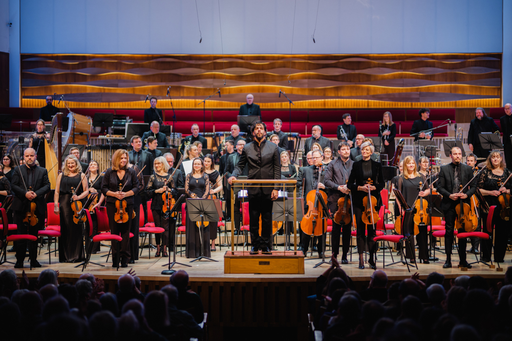 The Royal Liverpool Philharmonic Orchestra stands to applause, with conductor Domingo Hindoyan in front