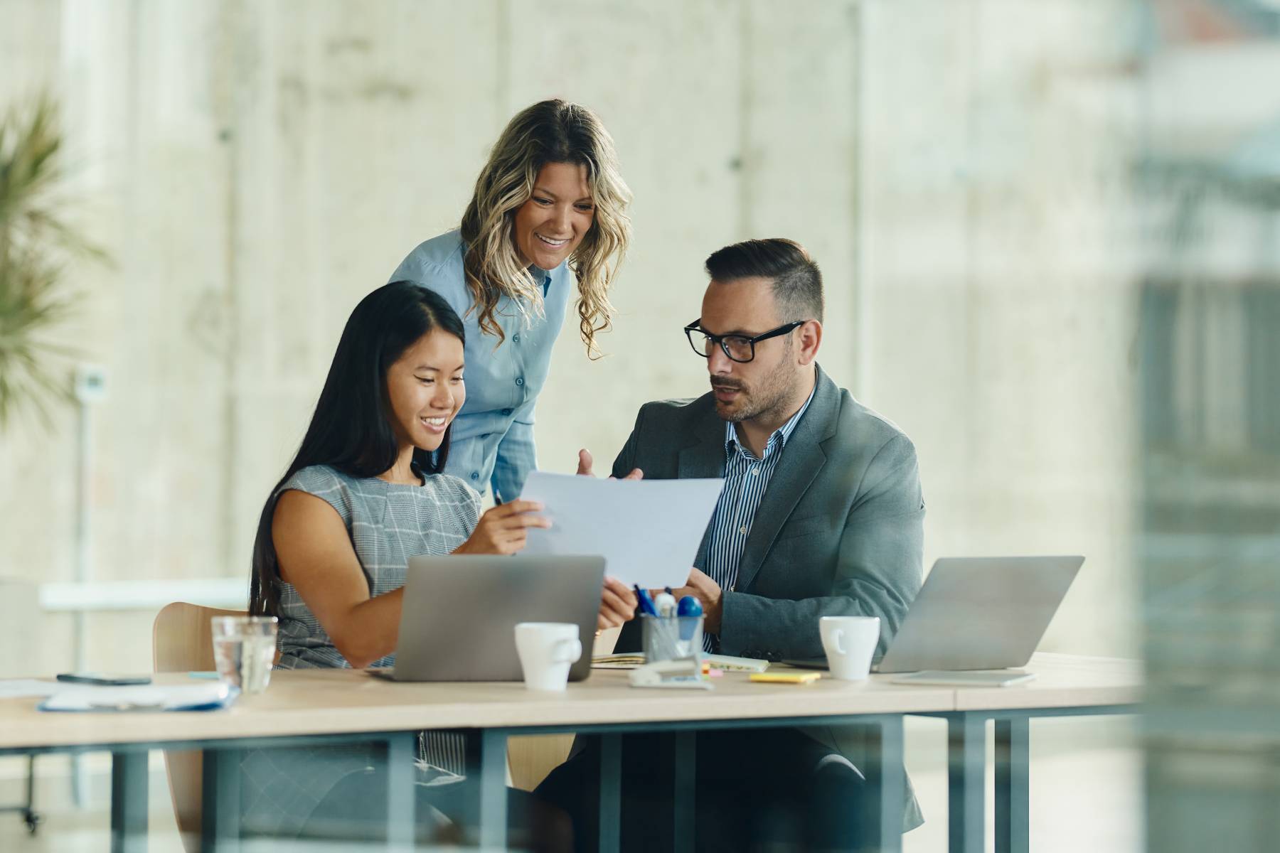 Three colleagues discuss a document together in an office