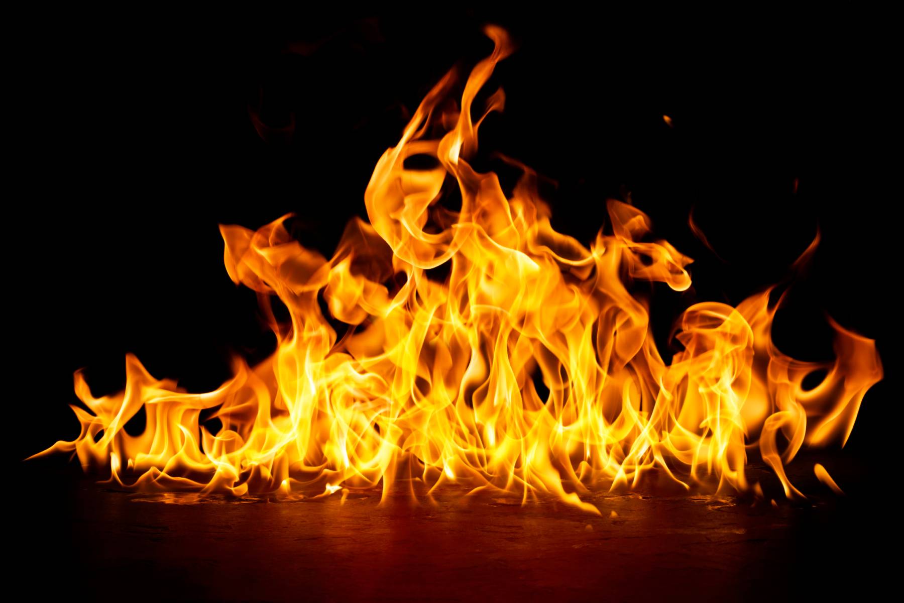 Yellow flames leap up from a fire burning on a concrete floor