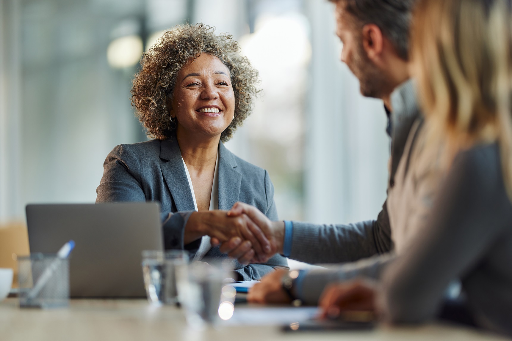 a woman sat down at a table shaking hands with a man and woman