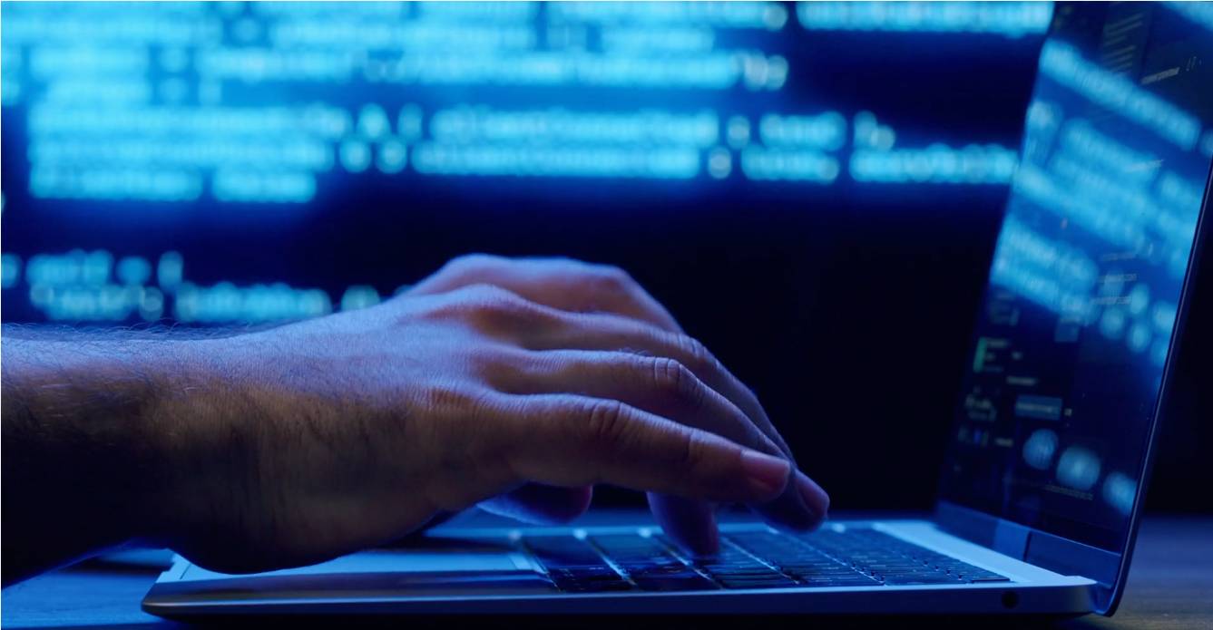 Fingers poised over a laptop keypad, with blue light in the background