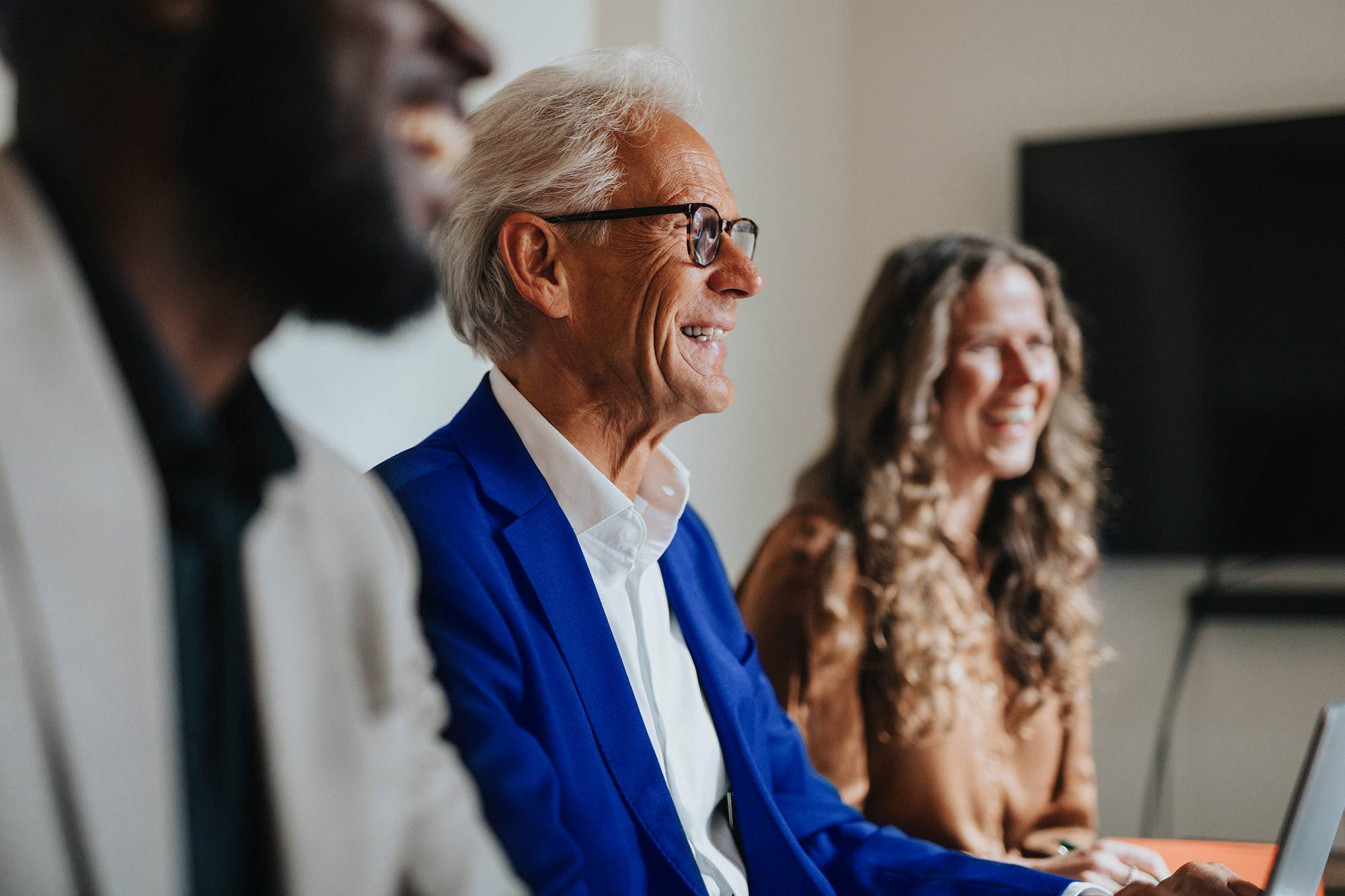 Three colleagues laugh together during a meeting