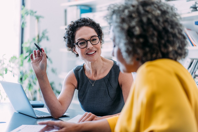 An adviser speaking with a client gathered around a laptop
