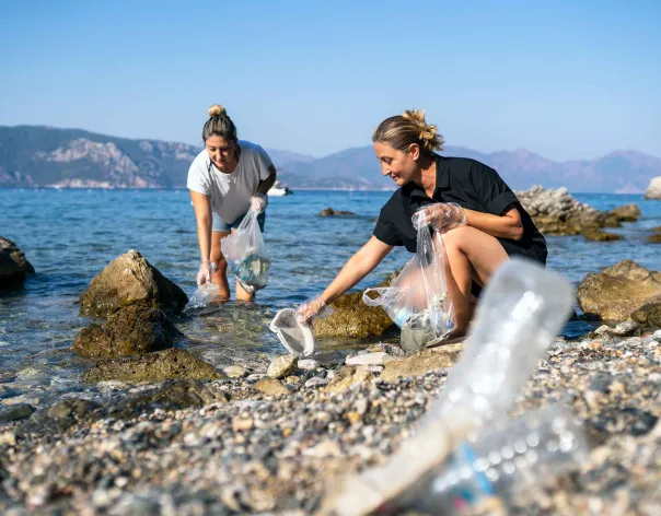 Two women collecting litter on a beach