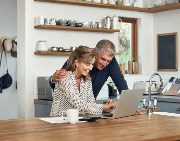 A couple look at a retirement plan on their laptop and discuss it together