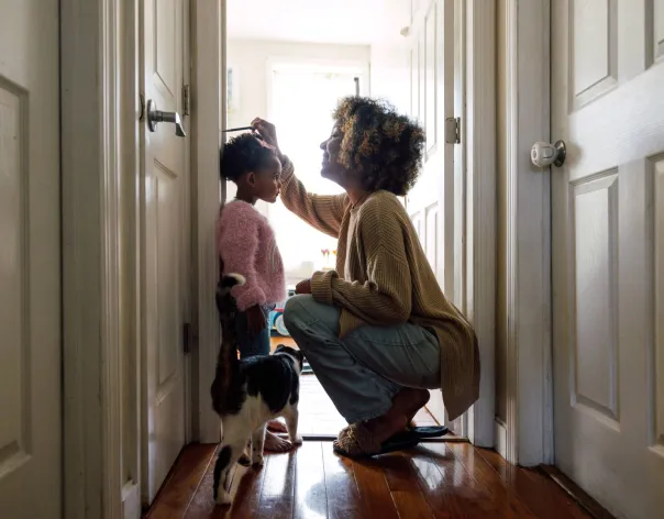 A mother measures the height of her child on a doorway