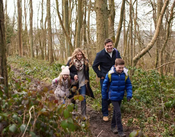 A family of four walking together through a wood