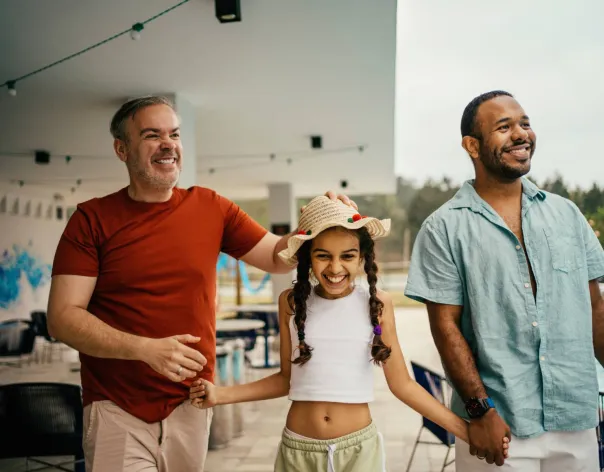 Fathers hold hands with their daughter at a public pool