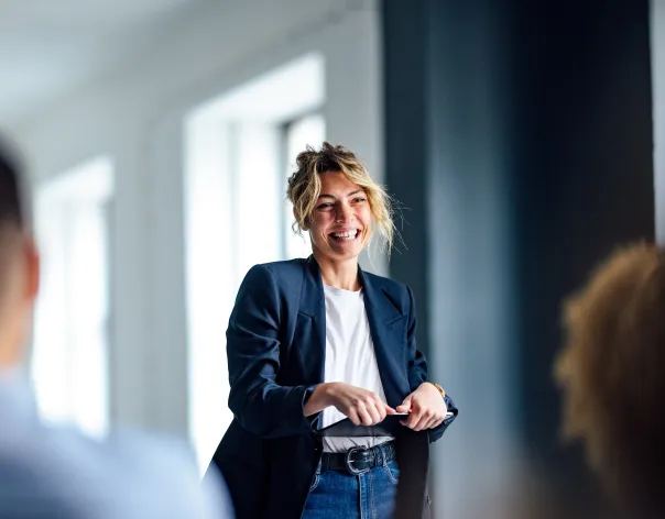 Woman holding an ipad stood up smiling in front of an audience
