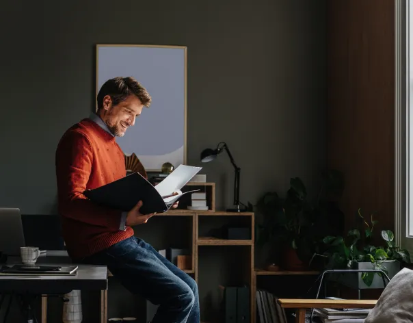 A charity trustee reading a file in his home office.
