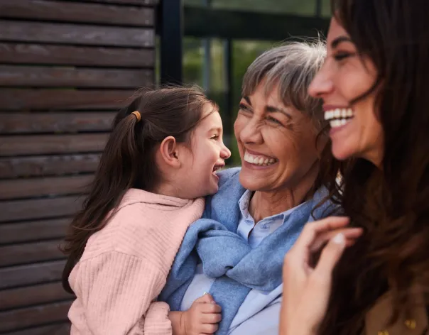 A grandmother embraces her daughter and granddaughter