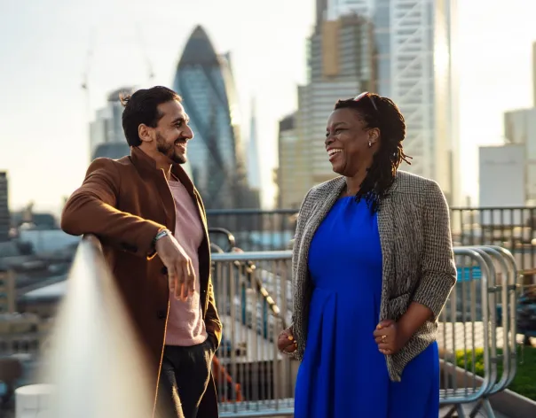 Two Rathbones colleagues laugh together while standing on our office terrace
