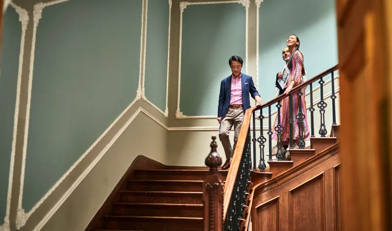 Young couple walking down the stairs of a stately home, behind an estate agent