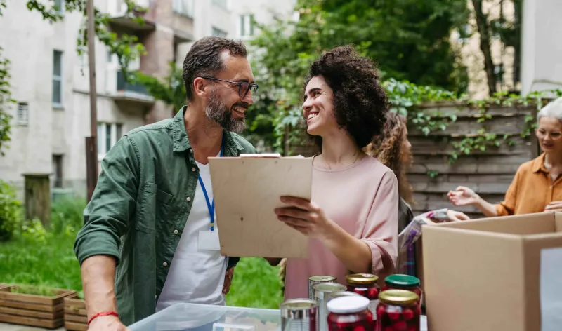 A man and lady volunteering outdoors to paint something for a charity