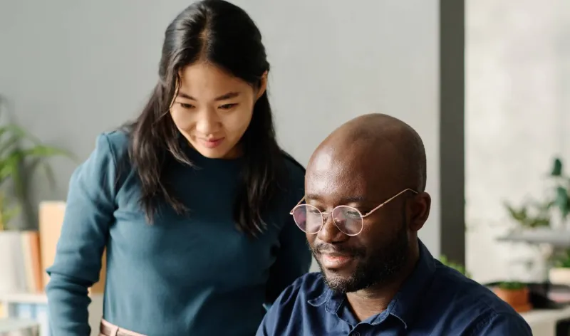 A man and woman discuss their finances while looking at a laptop