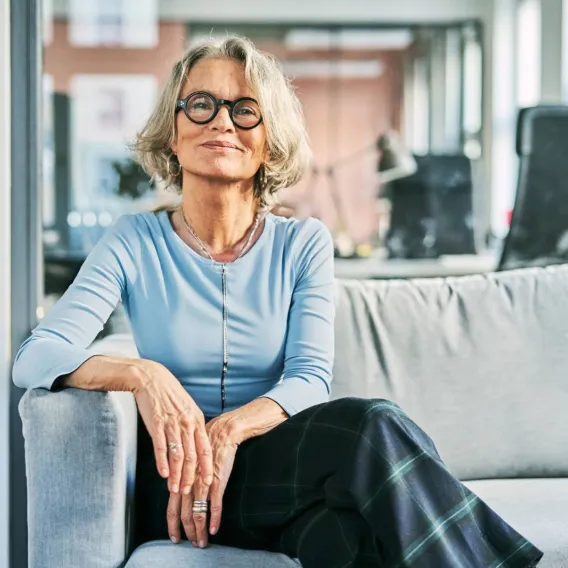 A lady sits on a sofa looking at the camera