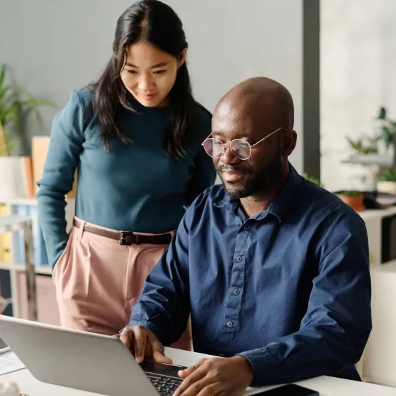 A man and woman discuss their finances while looking at a laptop
