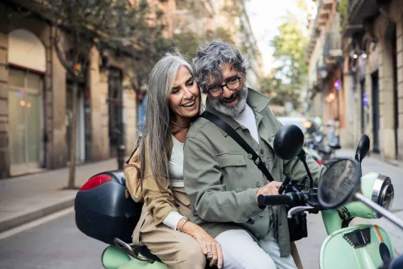 Man and women laughing on a vespa
