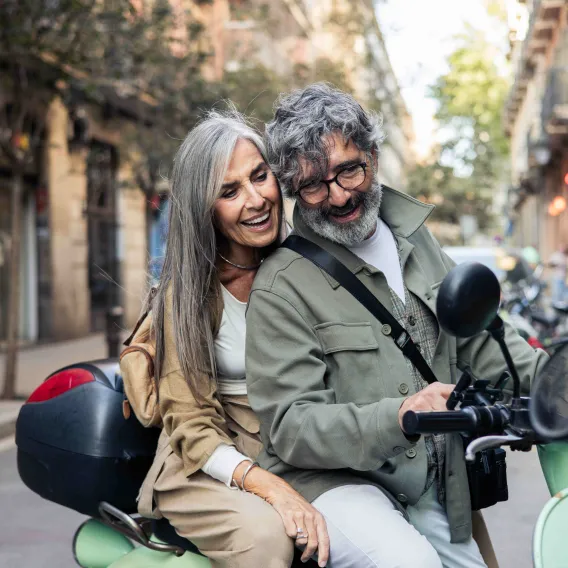 Man and women laughing on a vespa