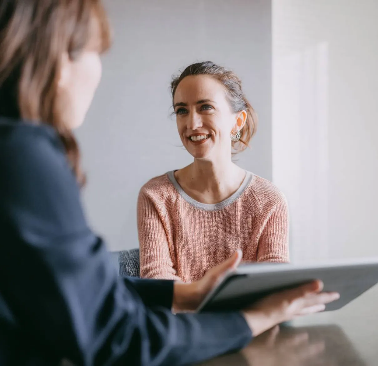 A financial adviser holds a tablet while meeting with a client