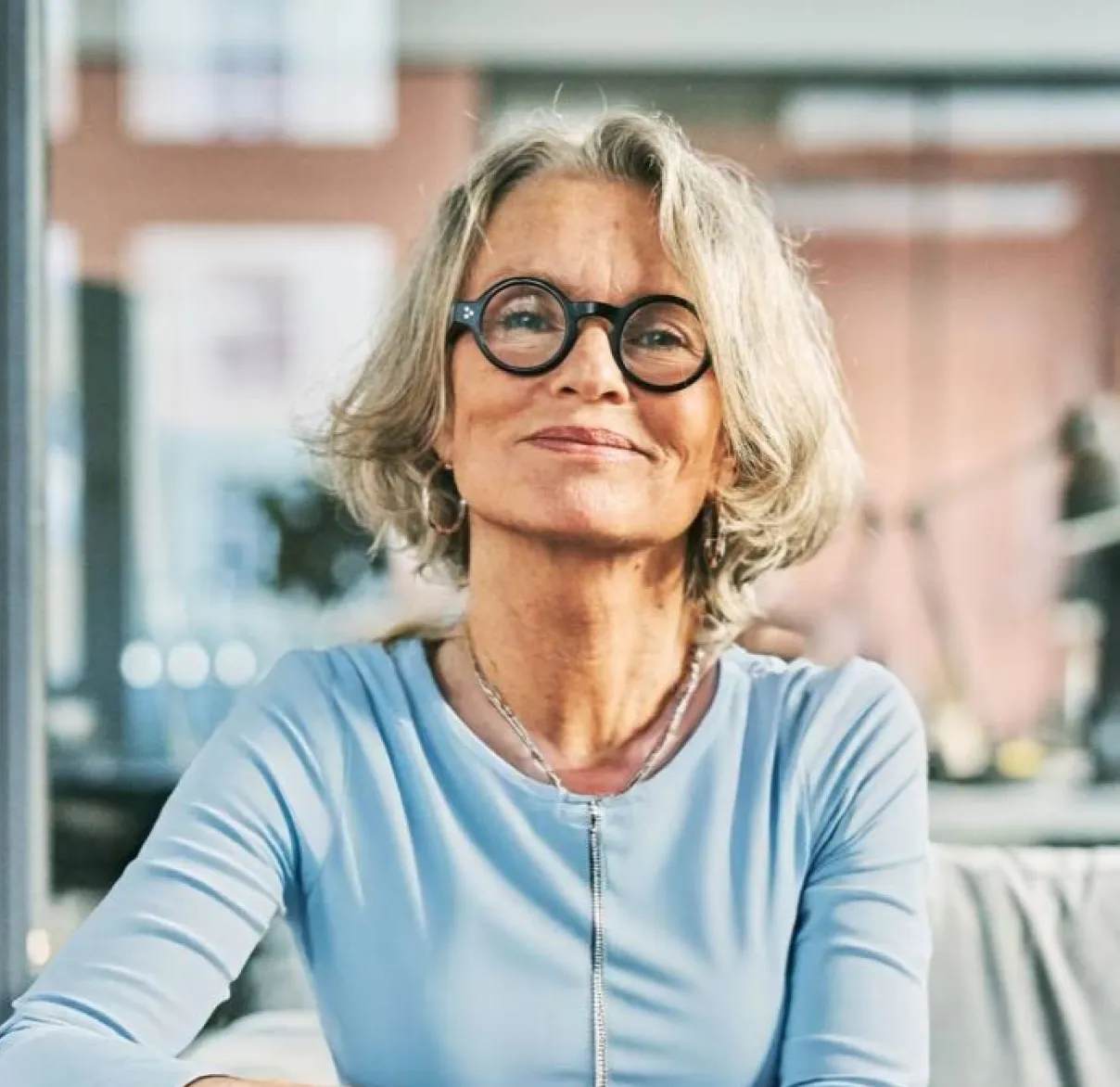 A lady sits on a sofa while looking at the camera