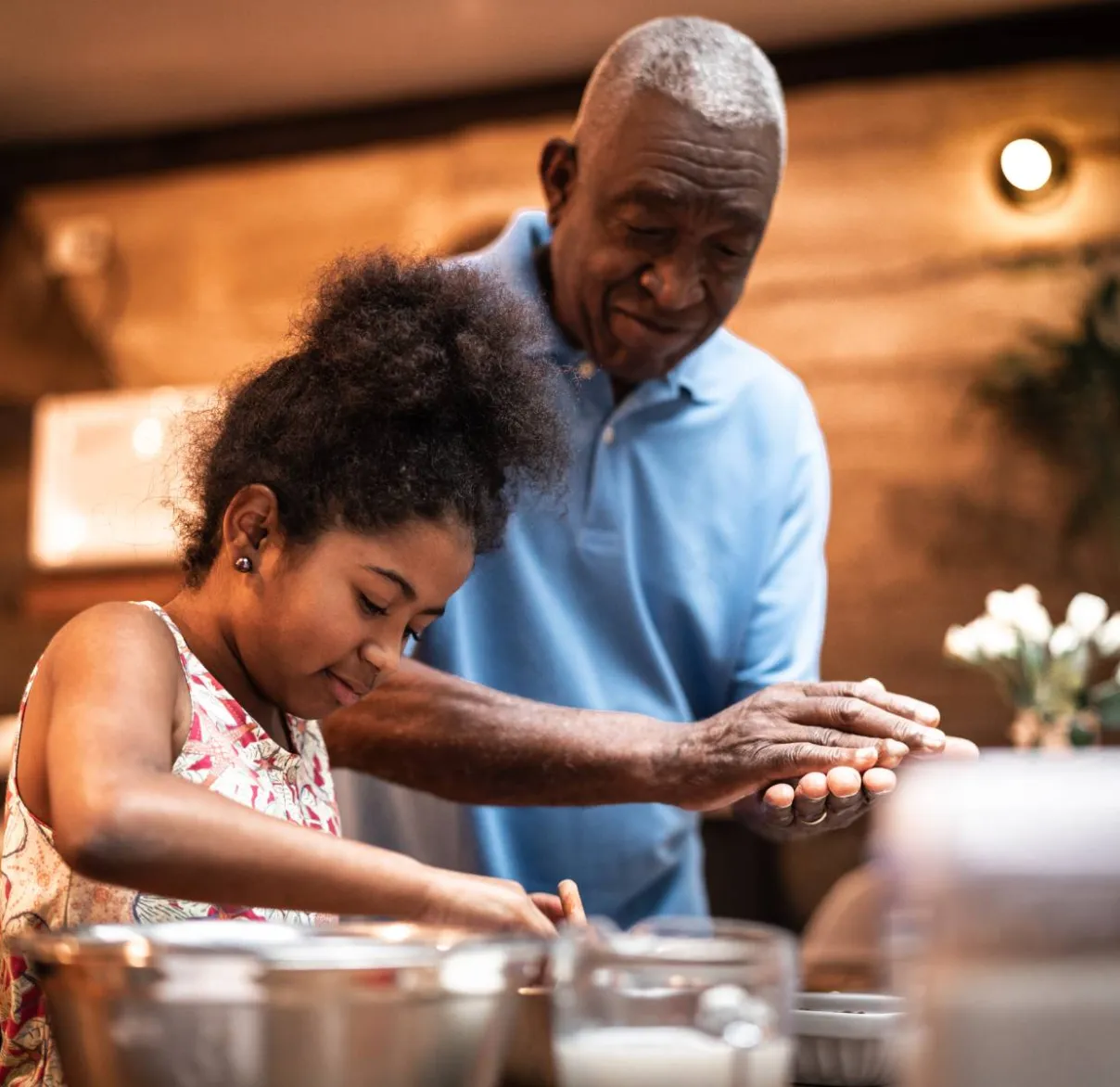 A grandfather makes a cake in the kitchen with the help of his granddaughter