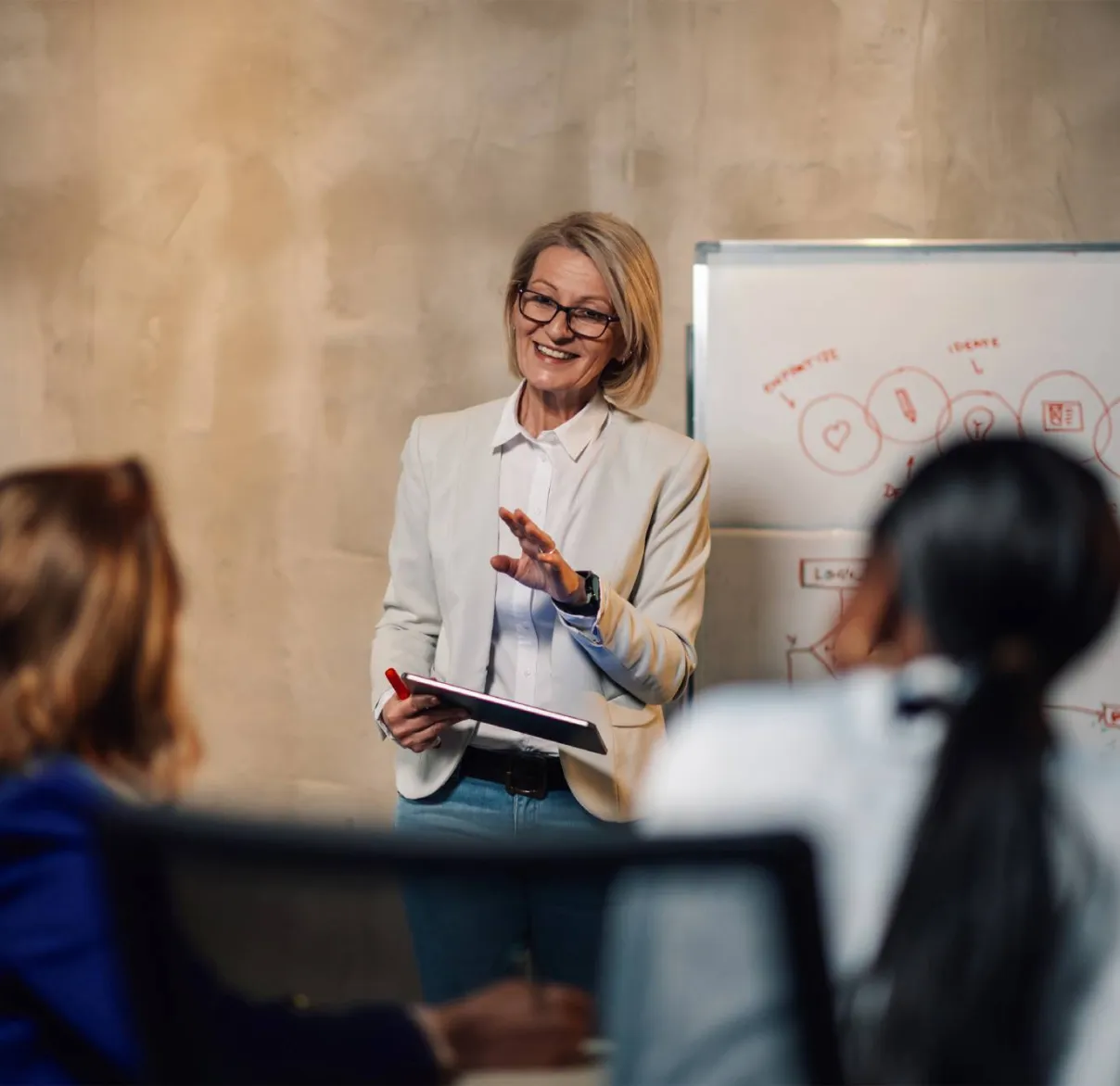 An instructor teaching to a classroom with whiteboard and tablet