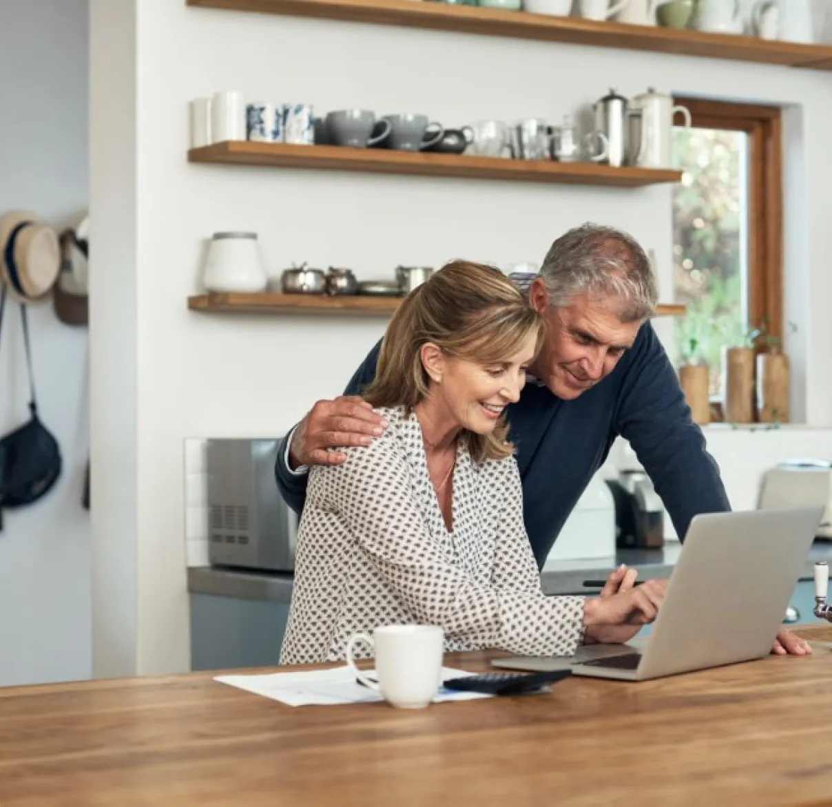 A couple look at a laptop together on their kitchen table