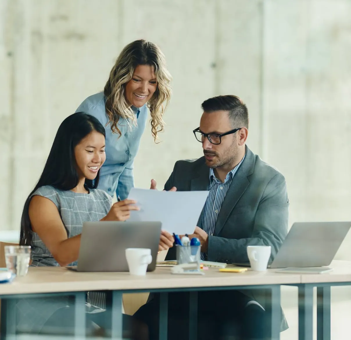 Three colleagues discuss a document together in an office