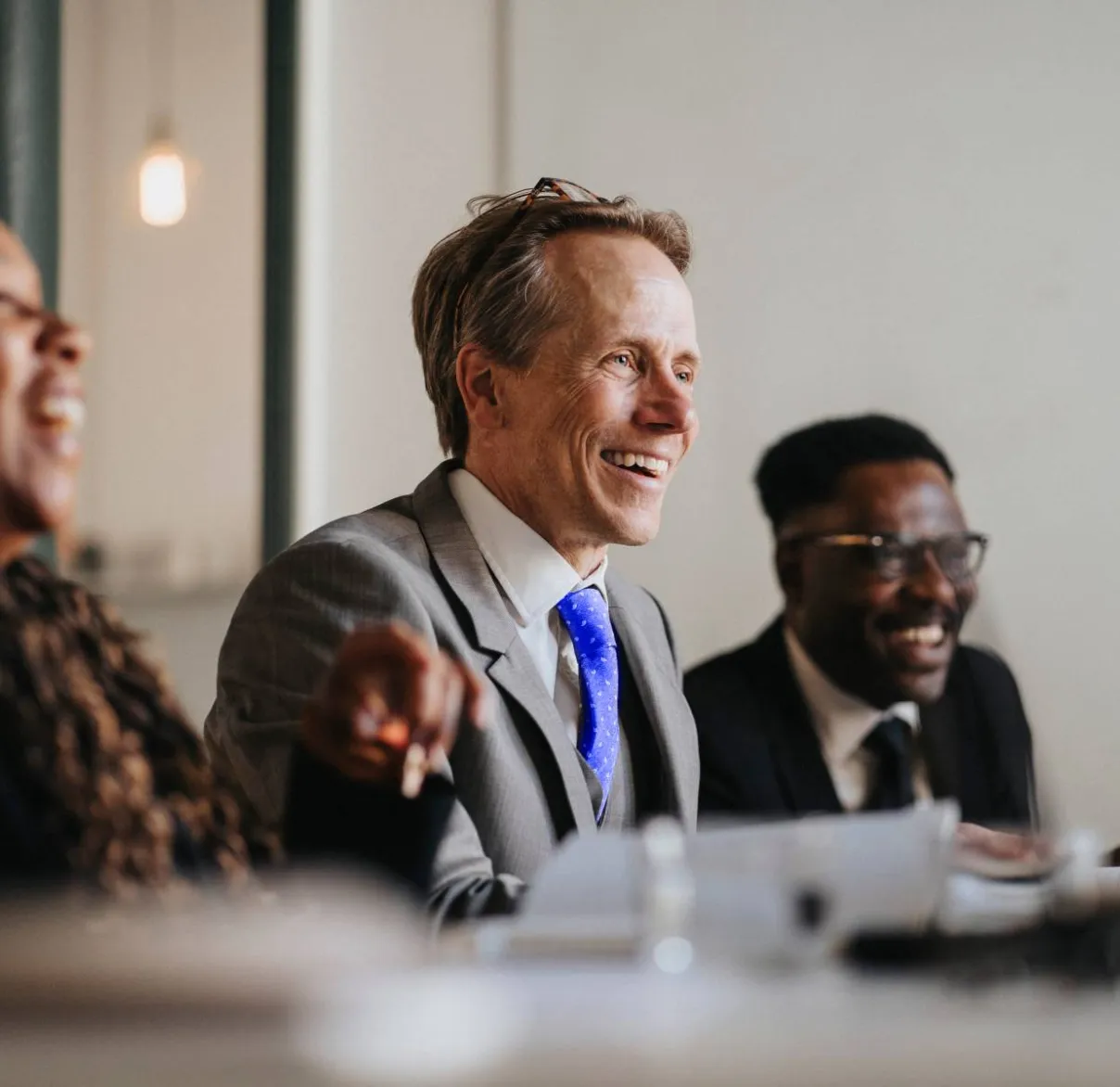 Three colleagues laugh during a meeting