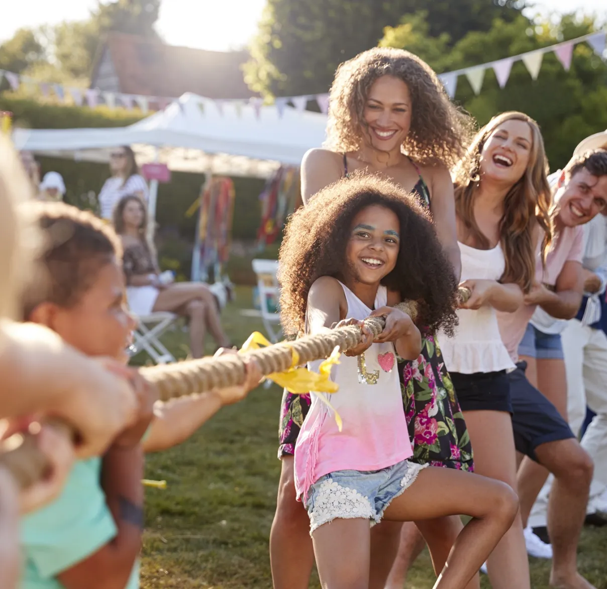 A group of adults and children playing tug of war at an outside charity trustee event