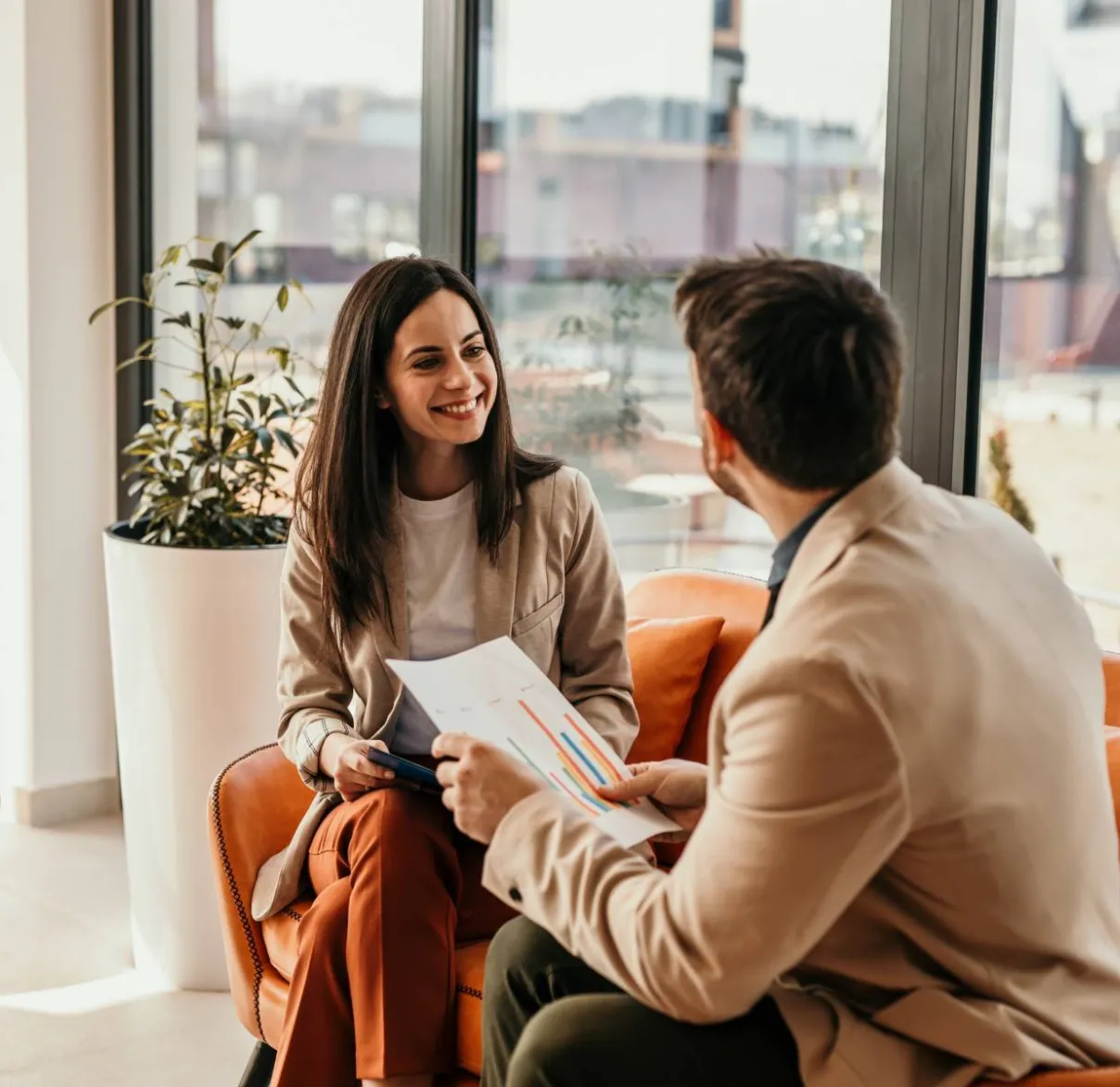 A financial adviser meets with their client on a sofa ijn a light-filled office
