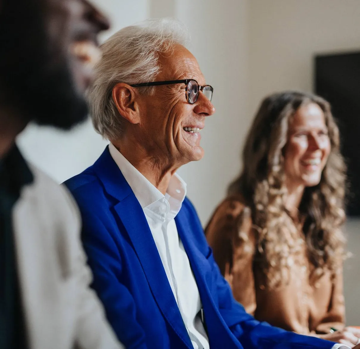 Colleagues laugh with one another while attending a meeting in an office