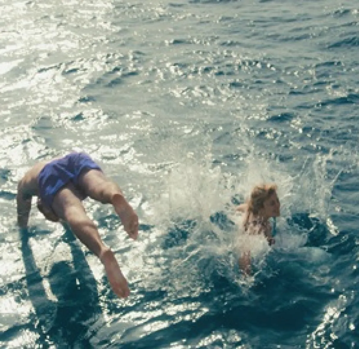 Father and daughter diving into blue water