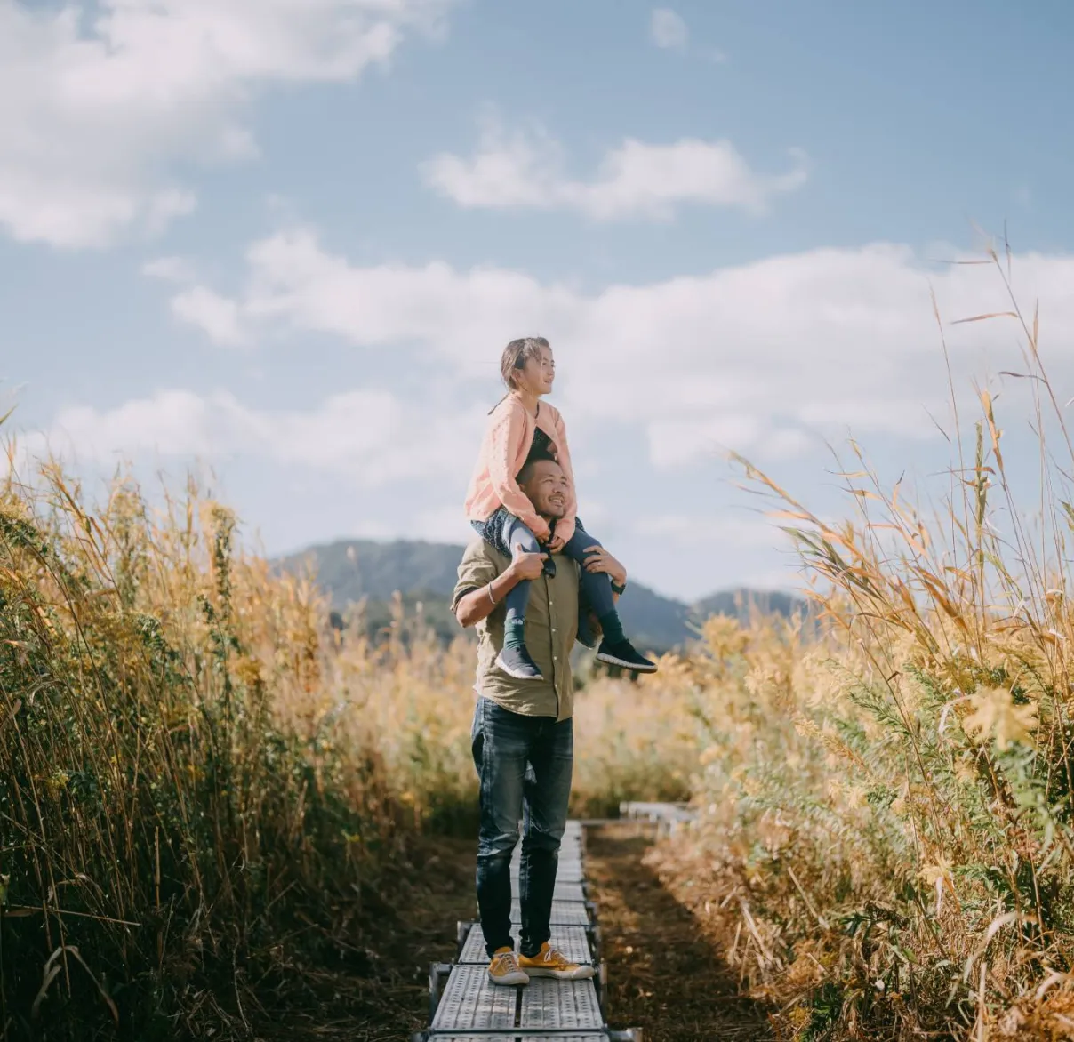 A father with his daughter on his shoulders stops to admire the view while on a wilderness walk