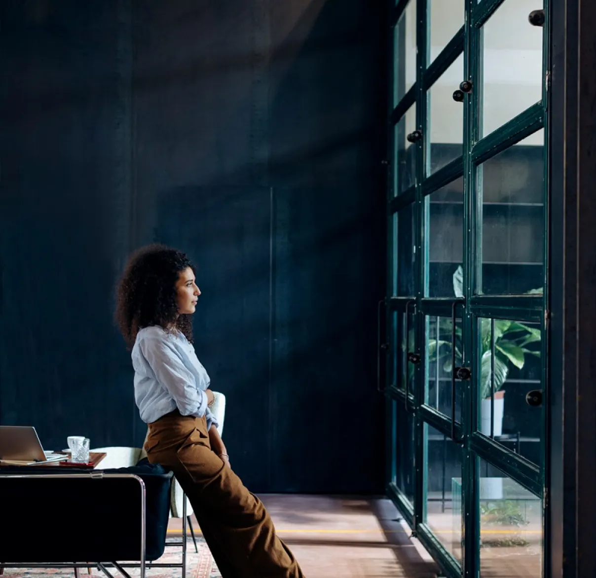 A lady looks out a window while standing in an industrial building