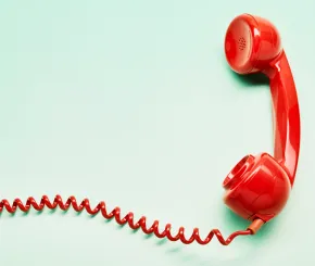 Red mid-century phone receiver on mint background with red coiled wire leading off canvas to the left