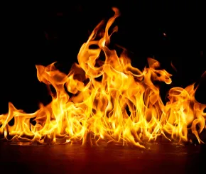 Yellow flames leap up from a fire burning on a concrete floor