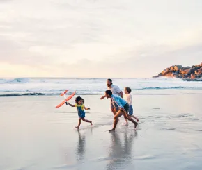 A family play together in the wash of the sea on a beach