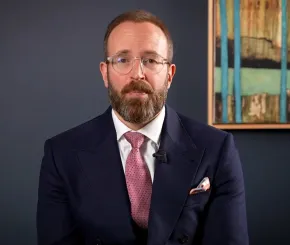 A still of a besuited Ed Smith speaking in a video update