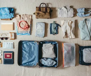 Folded clothing and travel items laid out ready for the suitcase