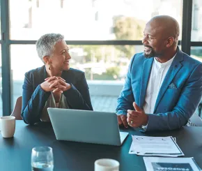 Man and woman sitting and talking in front of a laptop