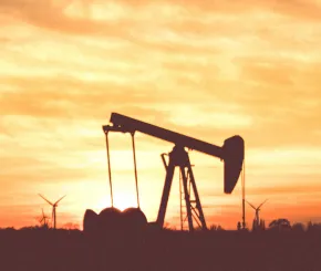 Silhouette image of oil rig with sunset in the background