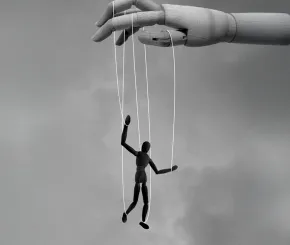 A wooden puppet hanging from strings held by a large wooden hand above